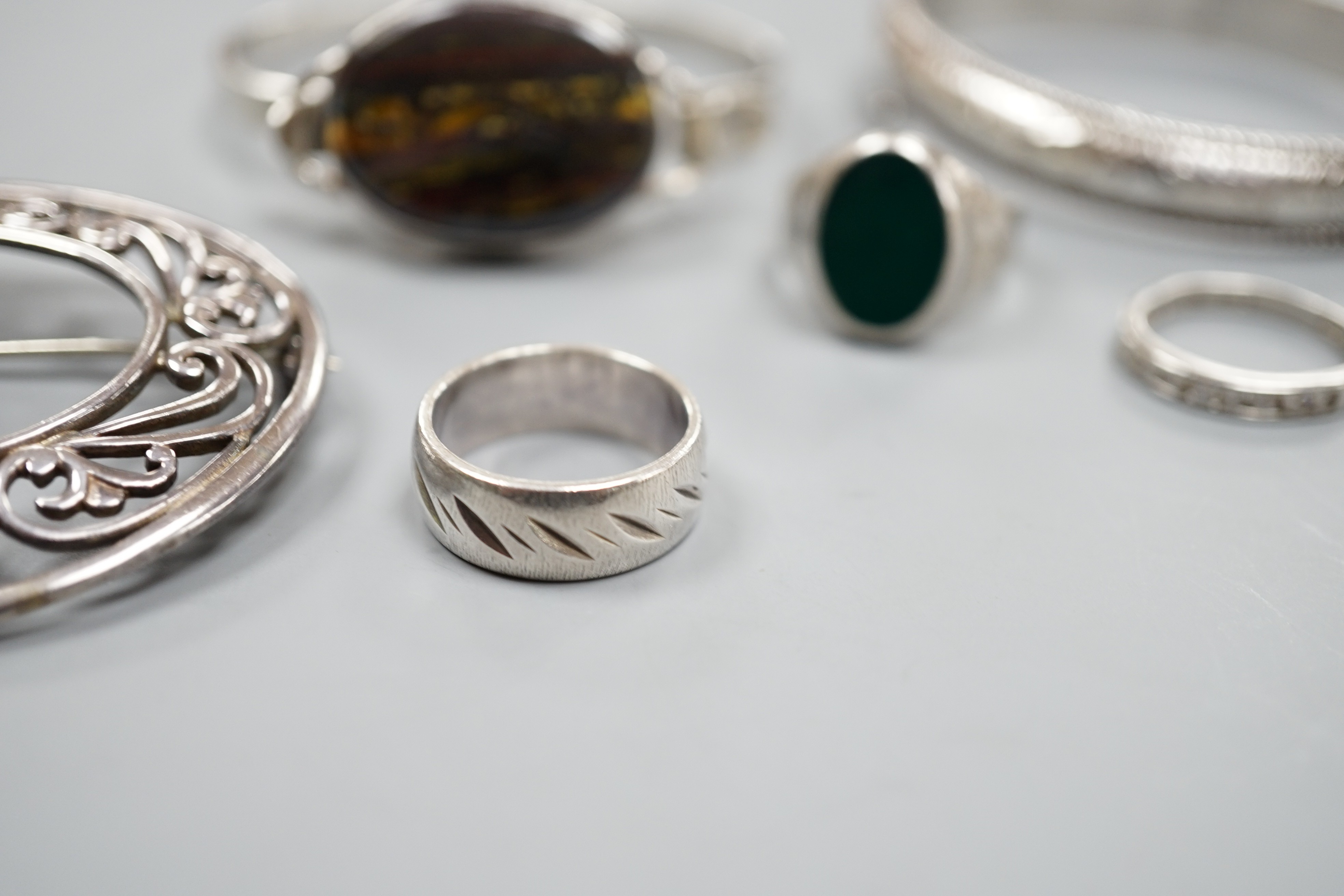 A 1970's silver and oval quartz set bangle, two other white metal bangles and three assorted rings.